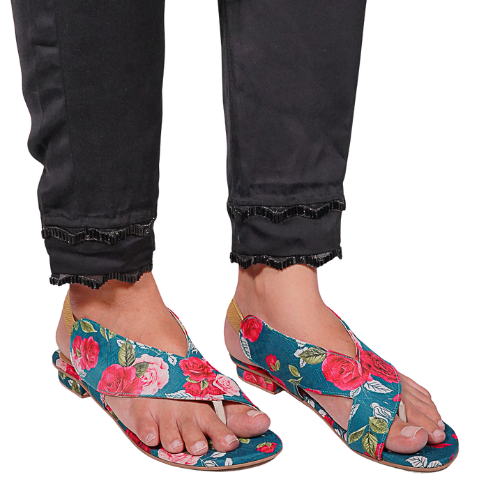 Floral sandals worn with black pants on a white background
